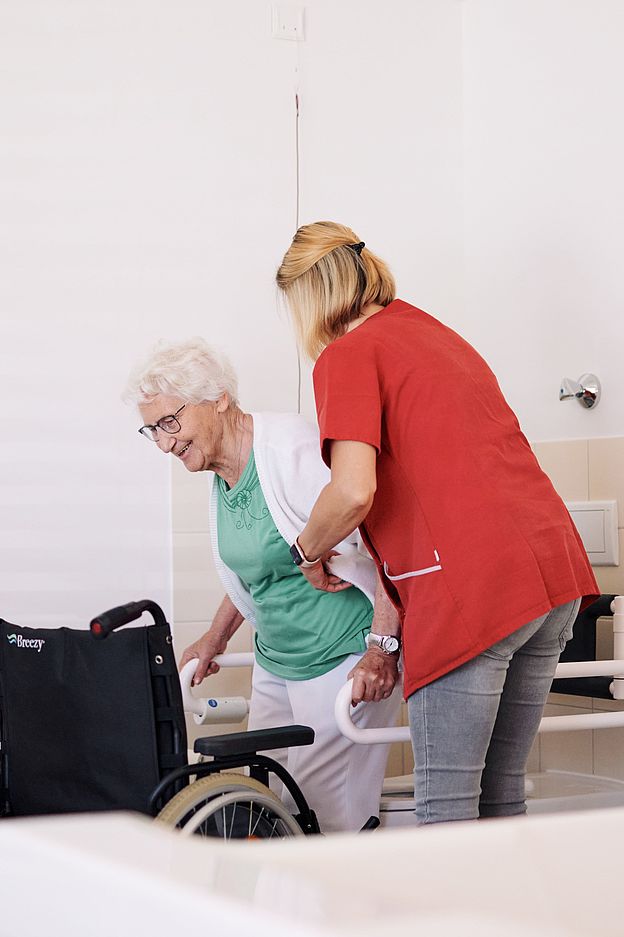 Ambulante Pflege Oebsifelde Eine Pflegefachkraft hilft einer älteren Damen in den Rollstuhl